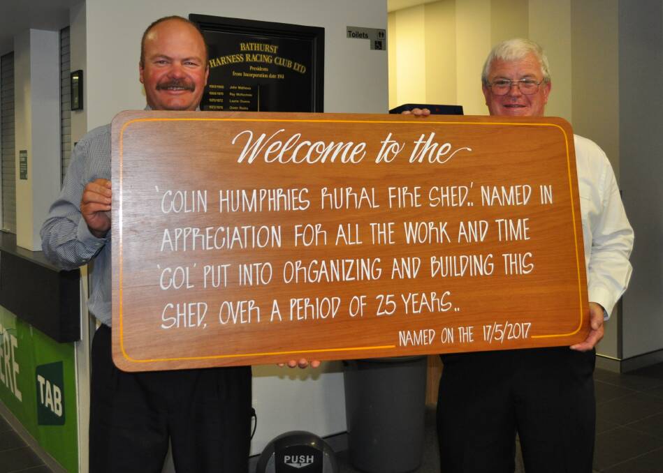 HONOURED: George Hancock and Colin Humphries holding the new sign for the Perthville/Georges Plains fire station. 110417rfs2