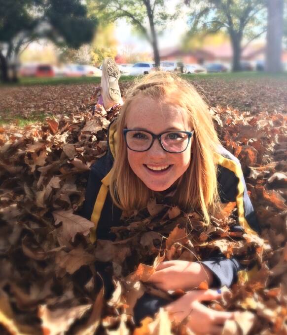 AUTUMN COLOURS: Natalie Davis, 17, is among many people who have enjoyed the autumn leaves in Machattie Park. Photo: LISA DAVIS 042817colours3