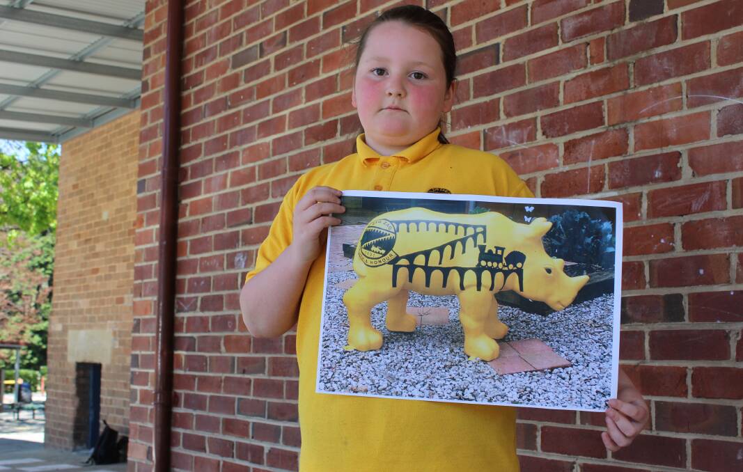 DEARLY MISSED: Zig Zag School student Chloe Murray holding a photo of Ziggle Zaggle, the school's rhino statue that was stolen this week. PHOTO: Jacob Gillard. lm102716zig