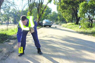 INVESTIGATION: Senior Constable Colin Crome at the scene of the fatal car crash on Hen and Chicken Lane. 042210bwcrash5