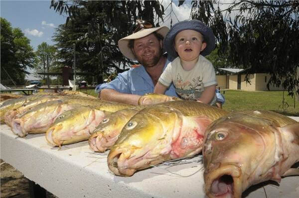 HOLY MACKEREL: Jim Squibb and his 19 months old son Dusty Squibb, who belied his age to reel in a fish almost as big as he is during the 200 BCF Carp Blitz on the Macquarie River at Bathurst. Photo: CHRIS SEABROOK. 110109carp5a