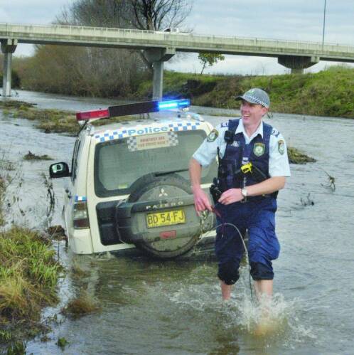 IN TOO DEEP: Senior Constable Phillip Mounce-Stephens tries in vain to rescue his police 4WD vehicle from the Macquarie River after becoming badly bogged near Eglinton yesterday morning. Photo: BRIAN WOOD
