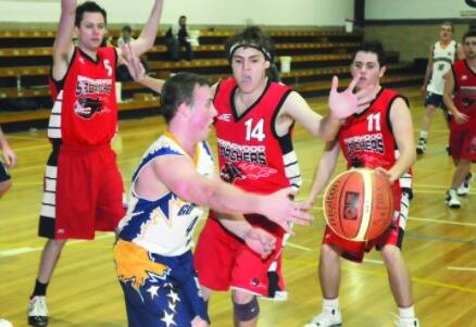 SURROUNDED: Goldminers skipper Kyle Simpson passes the ball back in court to a team-mate while under pressure from Springwood’s Matt Coates (#14). Photo: CHRIS SEABROOK 072410cgoldmy2