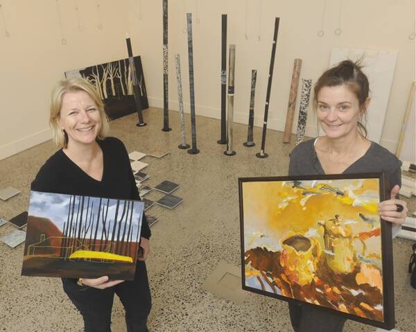 OFF THE WALL: Artist Julie Williams (with one of her works) and Janet Haslett (with a Genevieve Carroll piece) setting up at the Bathurst Regional Art Gallery this week. Photo: CHRIS SEABROOK 080811cbrag