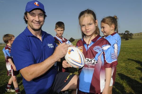 PEN PALS: NRL star Nathan Hindmarsh signs a football for Villages United Wildcats player Brandi Brown during yesterday’s visit. At the rear are two more Wildcats, Tyler Pears and Sophie Howe. Photo: CHRIS SEABROOK  092210cnath2