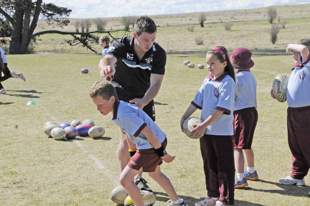 FUTURE STARS: Penrith Panthers' Doug Hewitt works with students from Holy Family School. Photo: PHILL MUURAY 092112pdoug
