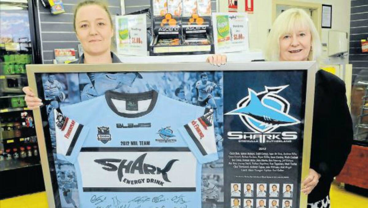 PERFECT FIT: BP Stewart Street assistant manager Marcelle Rawlings with the framed Cronulla Sharks jersey presented to the service station by Shark Energy Australia general manager Fiona Kay in recognition of the role it played in bringing the two organisations together. Photo: PHILL MURRAY