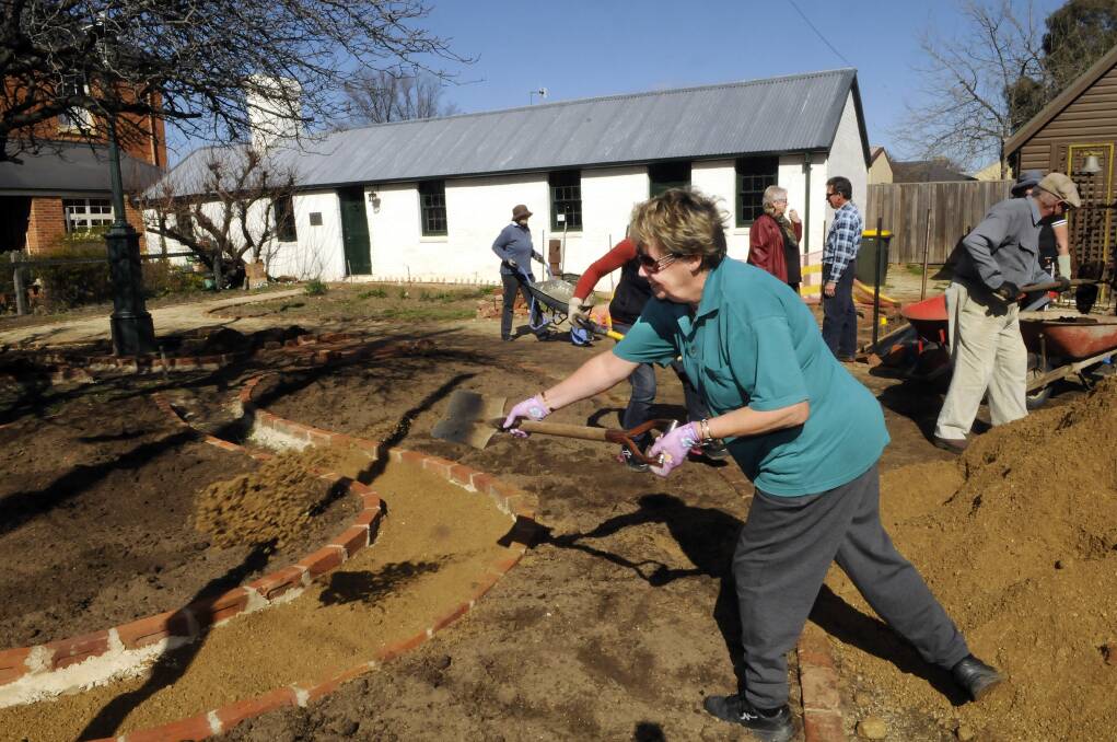 AUGUST: Anne Llewellyn of Bathurst Gardeners’ Club spreads out soil for one of the paths in the Old Government Cottage garden. Photo: PHILL MURRAY 081013pgarden