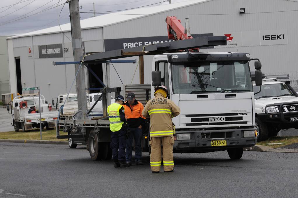 JUNE: A truck driver assists emergency services with their inquiries yesterday morning after the extendable arm mounted on his vehicle tore down power lines in Corporation Avenue. Photo: PHILL MURRAY 060713plines1