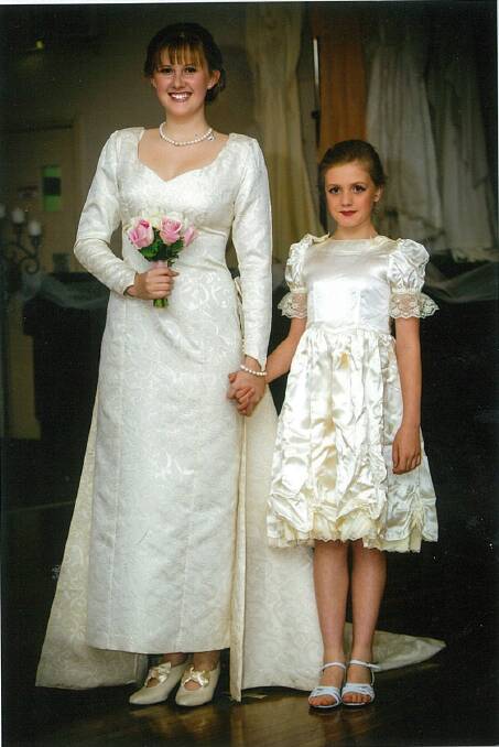 1996: Satin and gold embroidered princess-style long dress with long sleeves. The long detachable train was pleated and attached to the waist with a pleated band of flat bows and roses from the centre of the front of the dress. The dress was worn by Kerryl at her marriage in the 1990s and was worn at the show by her cousin, Jessica Elliott.
