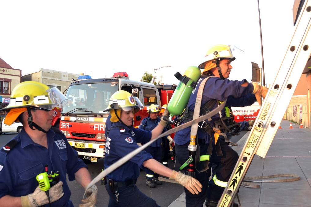 GRUELLING: Firefighters Ben Bignell, Peter Worrad and Tony Riley are put through their paces during a simulated house fire in the CBD on Tuesday as part of a NSW Fire and Rescue search and rescue training exercise. Photo: JACINTA CARROLL 010714jcfire1