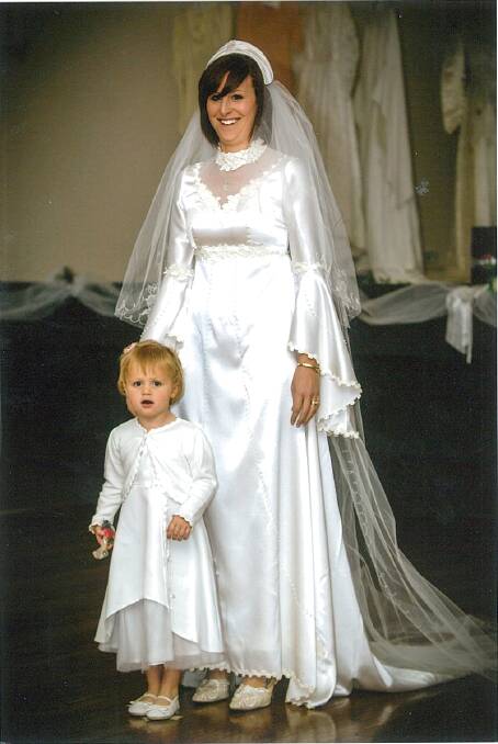 1970s: Soft satin dress with V neckline trimmed with lace. The veil was held in place by a satin band.
