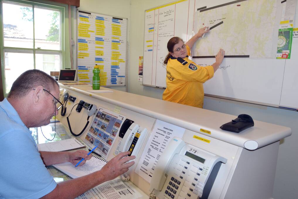 KEEPING UPDATED: Chifley Rural Fire Service member Greg Standen writes down messages relayed over the two-way radio, while deputy captain Paula Neill updates the Long Point bushfire’s location on the map at the RFS Chifley headquarters in Kelso. Photo: CHRIS SEABROOK 	010113cfrs