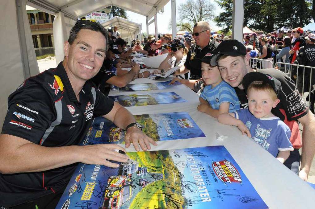 BATHURST: Craig Lowndes signs some posters for Nathaniel Mason with his nephews, Dominic(6) & Aiden Poisel(4)(from Bathurst).Photo: CHRIS SEABROOK