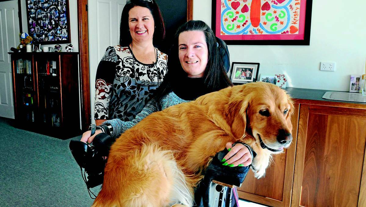 ORANGE: Nicole Sugden, who was involved in a devastating car accident ten years ago, is in the final stages of completing her PhD and is looking forward to face-to-face lecturing at CSU next term. She is pictured here with her mother Janine and Penny, the golden retriever given to Nicole as a puppy. Photo: STEVE GOSCH 0616nicole