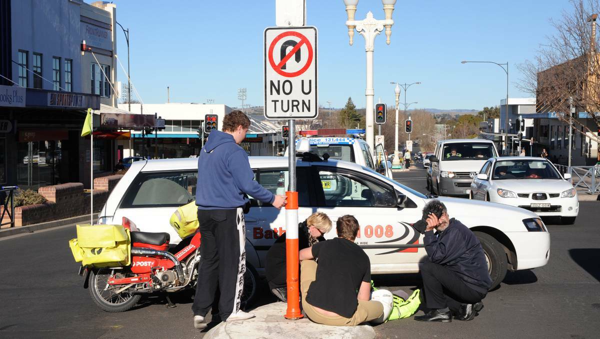 BATHURST: Bystanders assist a postie who collided with a taxi on Monday afternoon in Howick Street. Photo: ZENIO LAPKA 070113zprang