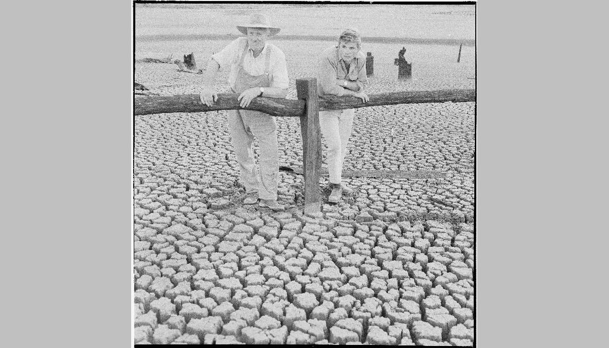 A farmer examines parched earth of an empty dam bed during drought, 1968. Photo: National Archives of Australia