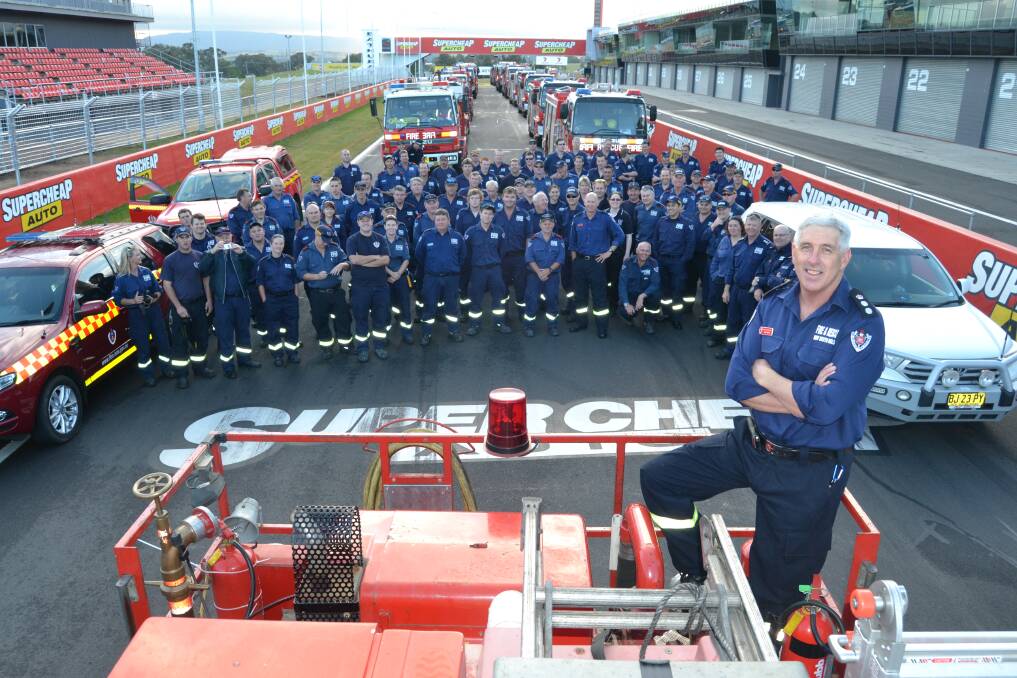 READY TO ROLL: Chief Superintendant Neil Harris with the 94 firefighters of Region West Strike Team and the 21 fire trucks which lined Pit Straight on the iconic Mount Panorama circuit yesterday morning prior to travelling in convoy to the Blue Mountains to assist with the firefighting effort. Photo: BRIAN WOOD 102313bwfire