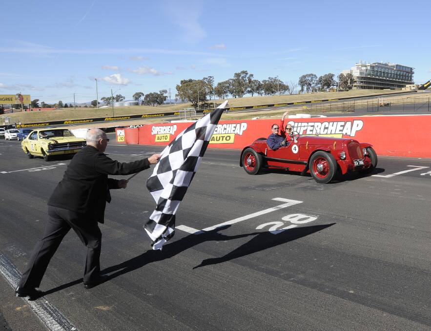 HOT SEAT: Councillor Graeme Hanger waves the chequered flag as Governor-General Quentin Bryce and Norm Rutherford complete a lap of Mount Panorama yesterday. Photo: CHRIS SEABROOK 051413cggv7b