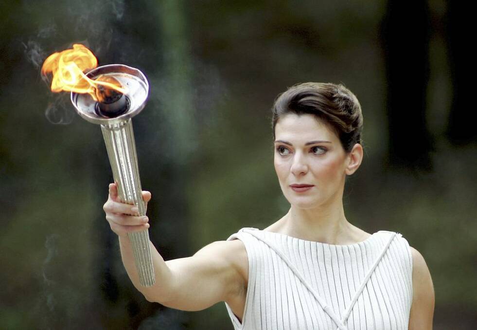 Theodora Siarkou, who plays the role of high priestess, holds the torch for the Turin 2006 Olympic Winter Games. Photo: Getty Images
