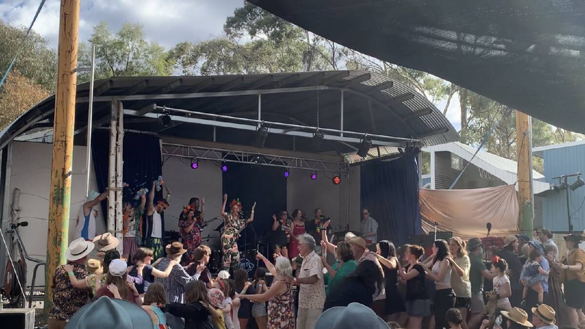Performers draped with feather boas sing Renee Geyer's Say I Love You on stage at Castlemaine Idyll 2023 and the audience groove along, forming a long conga line. Picture by Anna Houlahan