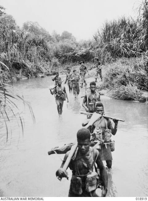 New Guinea, July 1945: Troops of the New Guinea Infantry Battalion wade through a stream on their way to attack a Japanese position.