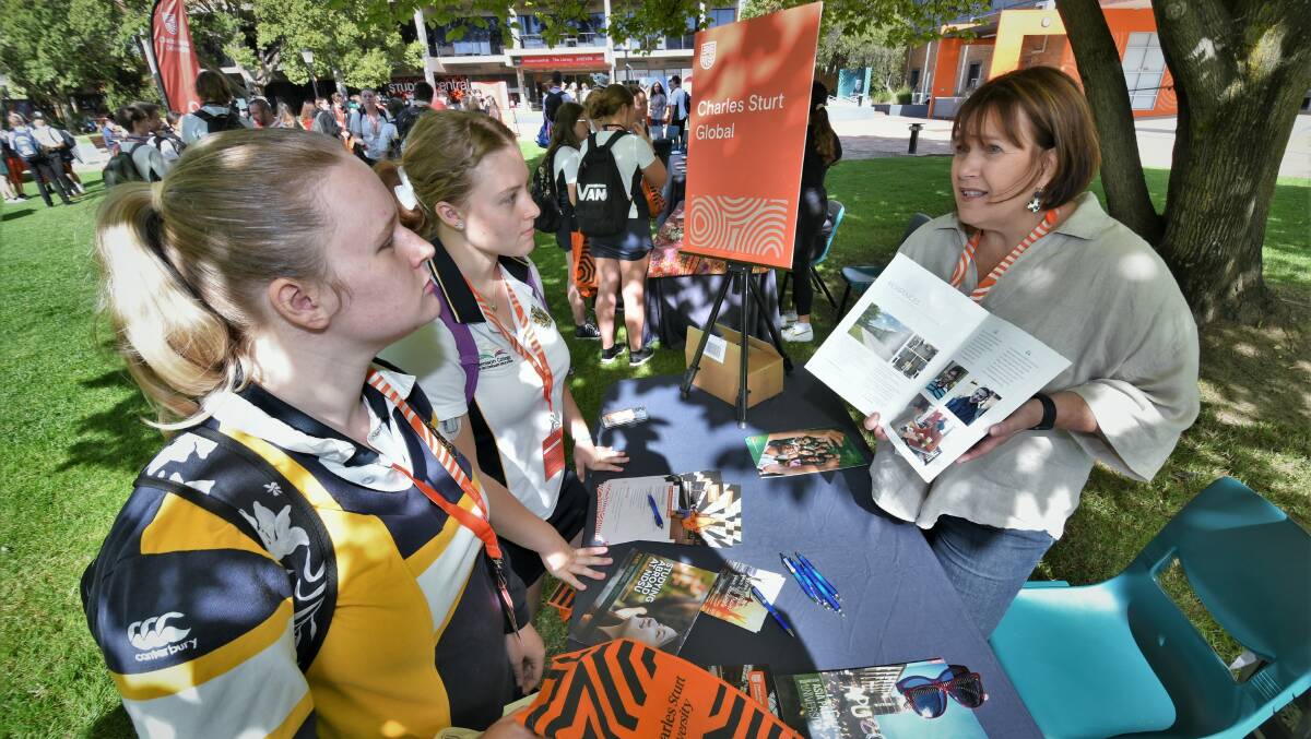 OPEN DAYS: Bathurst High Campus students Ebony Cannon with Chloe Boardman speaking with Louise Haberecht at the Charles Sturt Global stand at the CSU Explore Day back in March this year. Photo: CHRIS SEABROOK 031522csu2