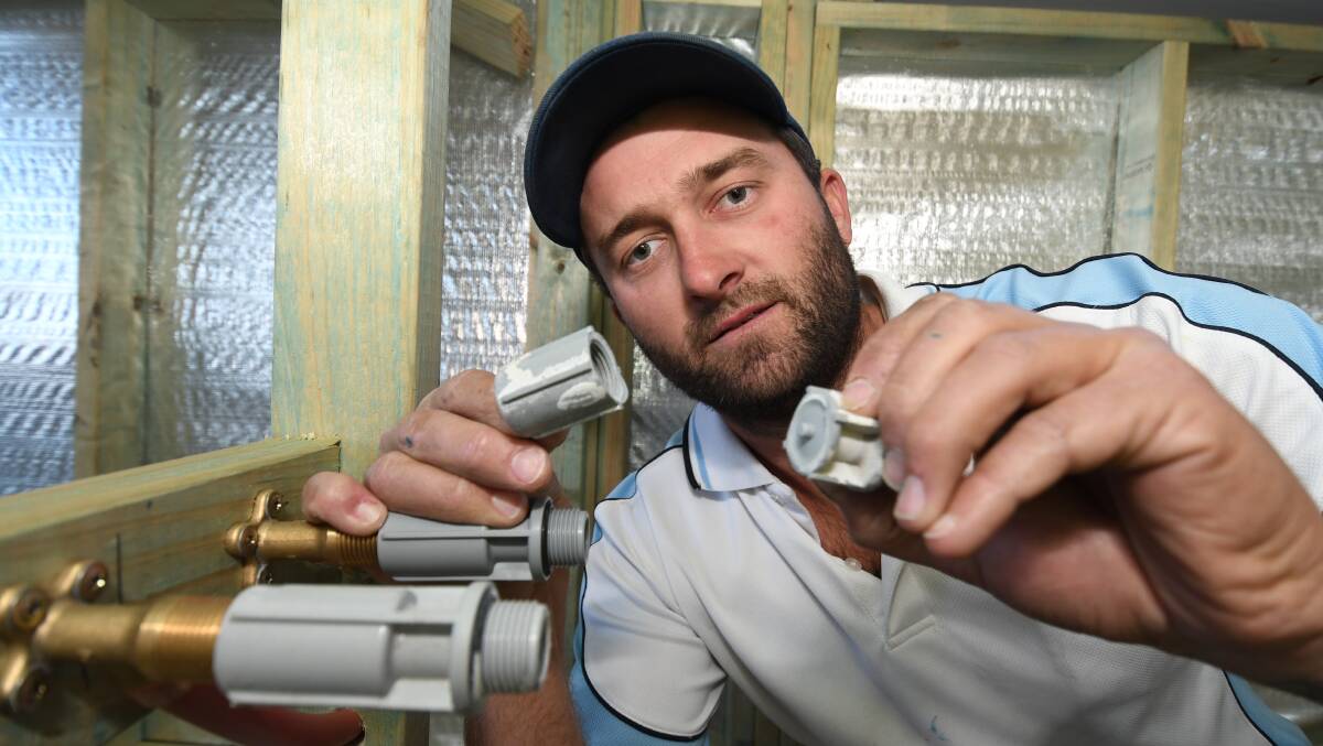 COVER UP: Bathurst plumber Geoff Bennett, with a plastic connector that was broken due to the severe frost on Monday. Photo: CHRIS SEABROOK 071718cpipes