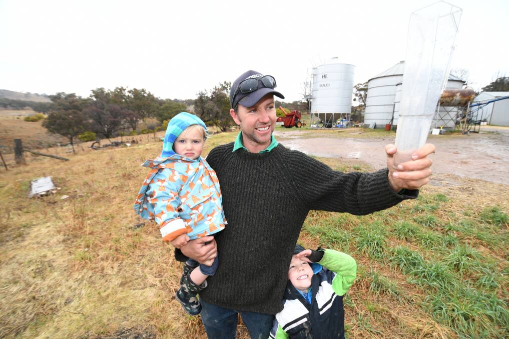 SOAKED: Farmer Charlie Dutton with his children two-year-old Clancy and five-year-old Hugh on his family's property on Tuesday. Photo: CHRIS SEABROOK 091719cwet2