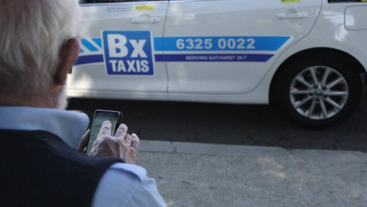 NEW LOOK: Bathurst taxi driver Dean Shadbolt on the Bathurst Taxis app, standing in front of a taxi with the new logo and phone number. Photo: BRADLEY JURD