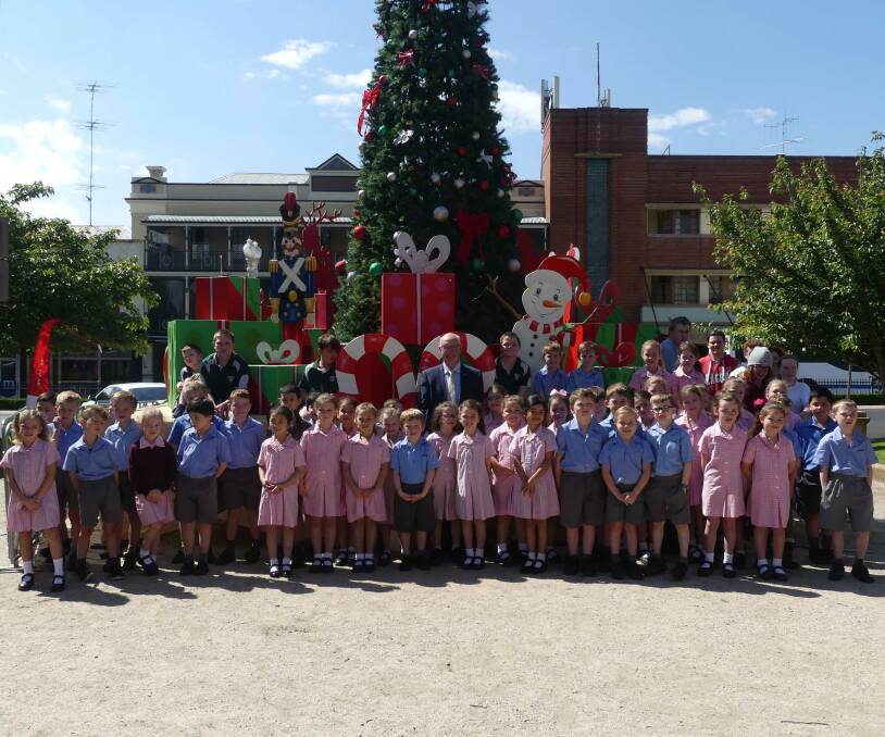 Merry Christmas: Students from Cathedral Primary School, Kelso Public School and Carenne Public School with the Christmas tree in Kings Parade.