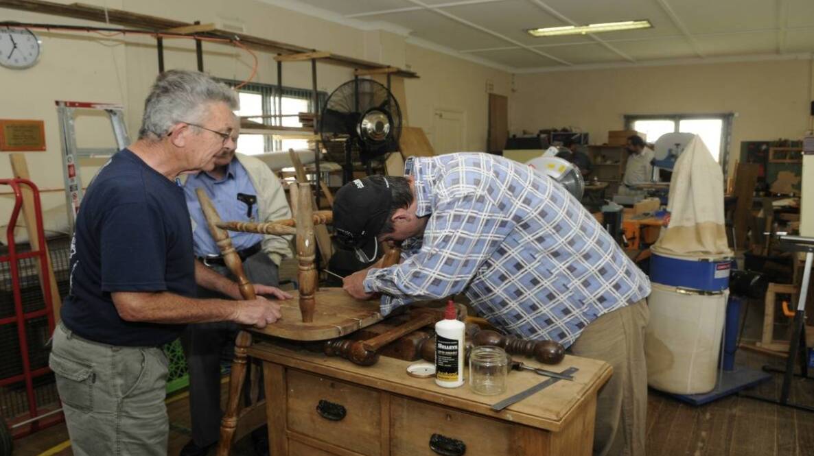 MEN AT WORK: Bathurst Men's Shed members restoring an old chair. Photo: PHILL MURRAY