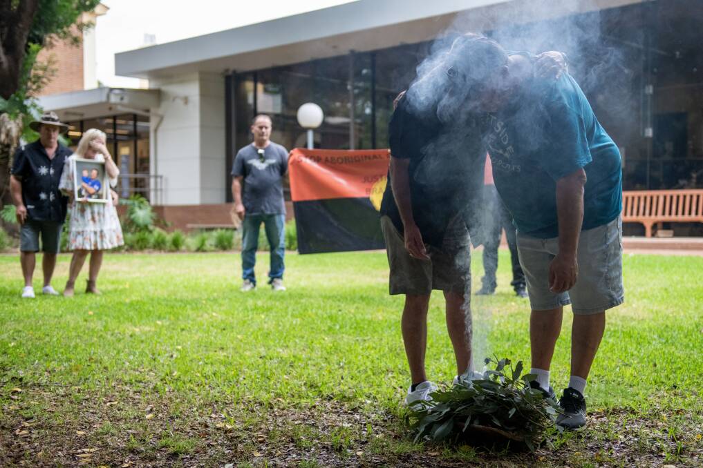 Family members hold each other during a smoking ceremony at Dubbo Court House. Picture by Belinda Soole 