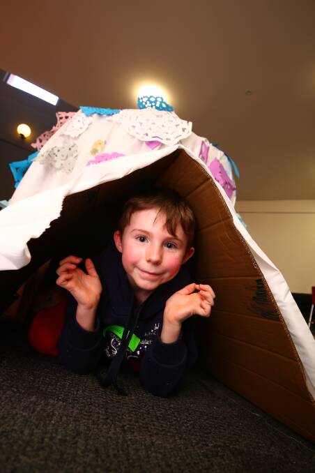 WHO'S THERE?: Lucas Milne, 7, inside the giant igloo made and decorated by kids during a school holiday workshop at Bathurst Library on Monday. Photo: PHIL BLATCH 070918pbhol1