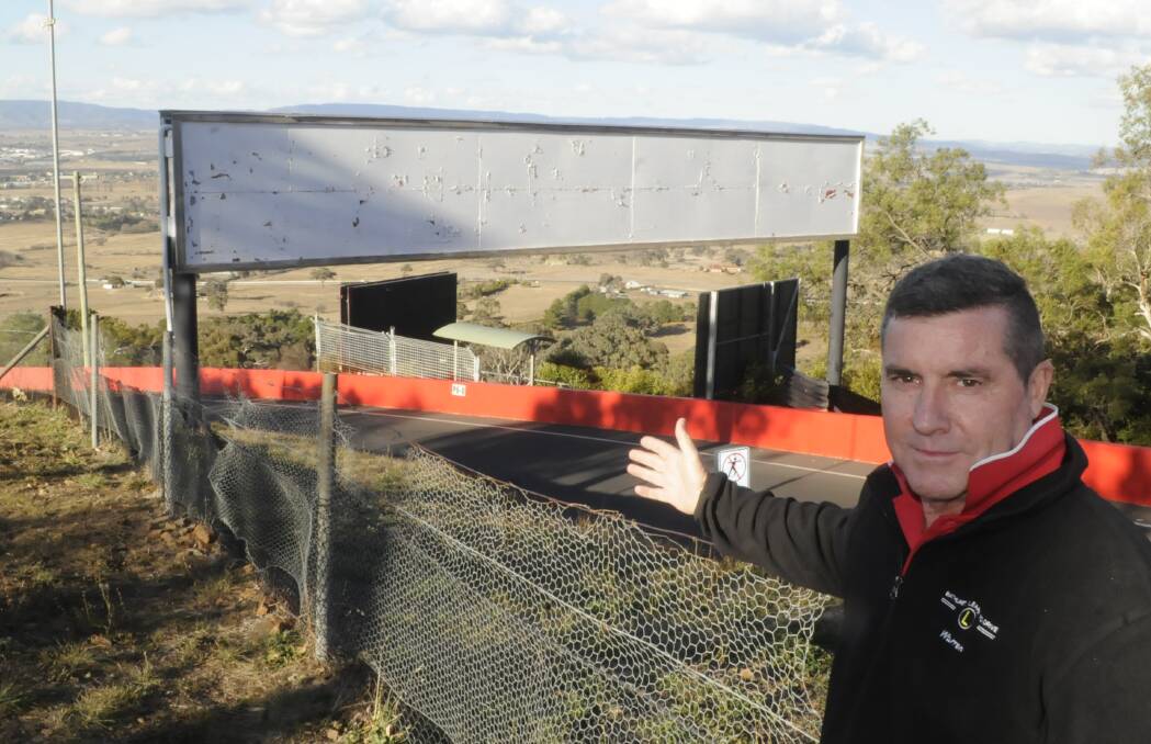 EMPTY SPACE: Councillor Warren Aubin at Mount Panorama in 2017, when he was highlighting the need to use the empty billboards between race events. 