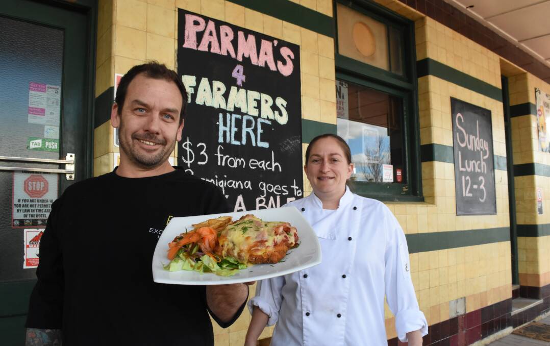 HUNGRY TO HELP: Bathurst resident and Blayney's Exchange Hotel publican Marty Russell and the pub's chef Kathryn Cumberland with one of their chicken parmas. Photo: MARK LOGAN.