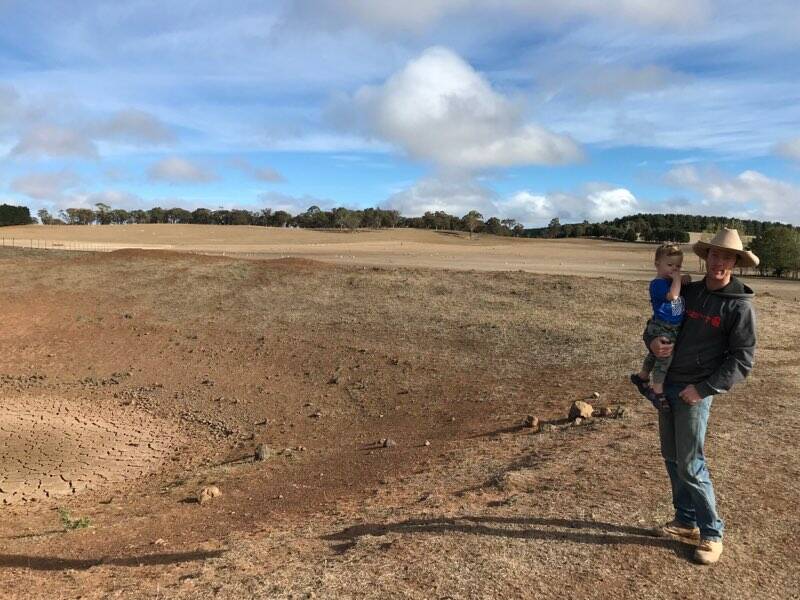 DRY TIMES: James Gilmore and his son Hudson, 2, with one of the many dry dams on their Black Springs property. Photo: SUPPLIED