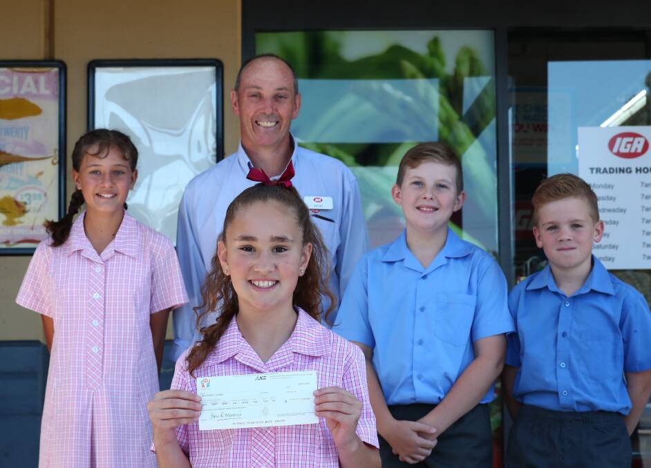 CHEQUE IT OUT: IGA Trinity Heights manager Kevin Allen presents a cheque for $1722.88 to Holy Family captains Chloe Brasier, Lily Sharwood (front), Jake Henry and Miles Barrett. Photo: PHIL BLATCH 020518pbholy1