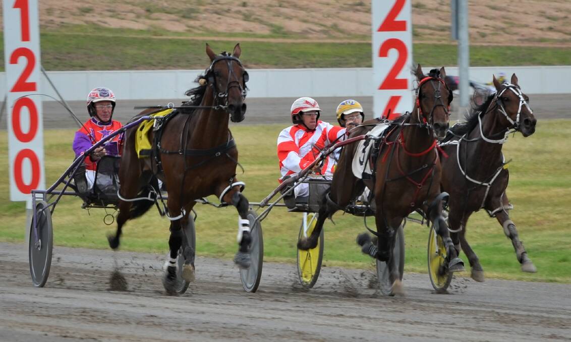 HERE HE COMES: Kashed Up (left), with Bernie Hewitt in the gig, makes his charge to the lead down the home straight at the Bathurst Paceway. Photo: ANYA WHITELAW
