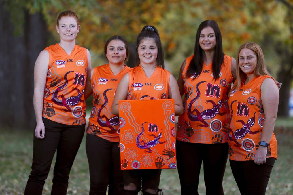 INDIGENOUS ROUND: Katie Kennedy, Maddy Booth, Dakota Nugent, Sarah Taylor and Hailee Provest in the Giants' jumpers and posing with the painting they are based on. Photo: PHIL BLATCH