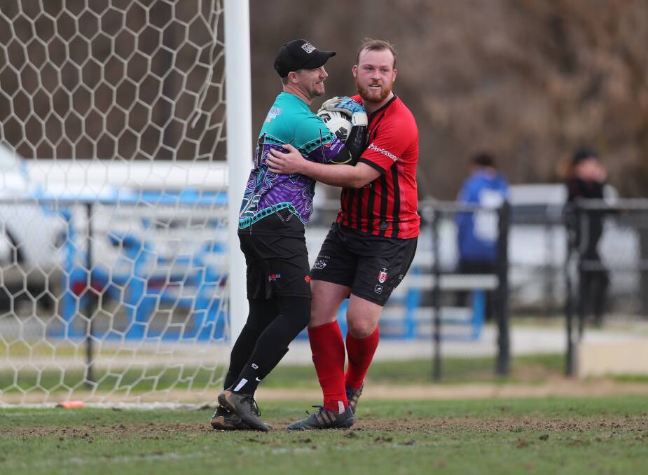 FRIENDLY RIVALS: Dubbo Bulls goalkeeper Hayden Williams and Panorama FC striker Ryan Peacock share a friendly hug in Saturday's Western Premier League match. Photo: PHIL BLATCH