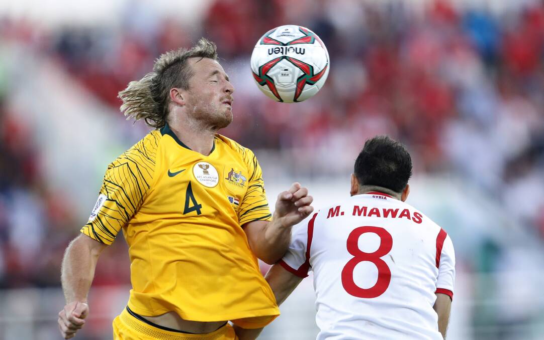 HEADS UP: Bathurst District Football graduate Ryan Grant wins a defensive header in the Socceroos Asian Cup match against Syria. Photo: AP