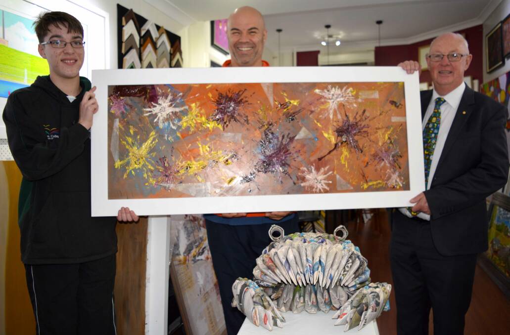 WASTE NOT: TJ Henderson is awarded his prize by Bathurst artist Dean Mobbs and Bathurst mayor Graeme Hanger. TJ's winning artwork, the newspaper frog, is pictured in the foreground. Photo: SUPPLIED