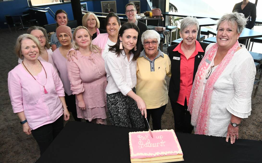 IN THE PINK: Meg McKenna (centre) cuts the cake at the Pink Up Bathurst launch at Bathurst Memorial Centre on Tuesday. Photo: CHRIS SEABROOK 100119cpinkake