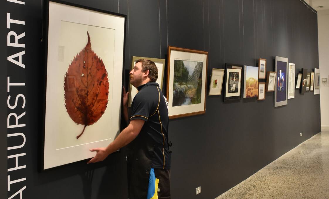 IT'S BACK: Gallery assistant James Bruce helps install the sixth Bathurst Art Fair back in 2017. Photo: SUPPLIED
