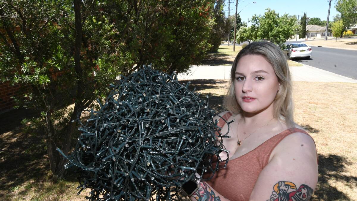 VANDALISED: Rankin Street resident, Clare Eastlake with her cut up Christmas lights that had been hanging in the trees behind her. Photo: CHRIS SEABROOK 