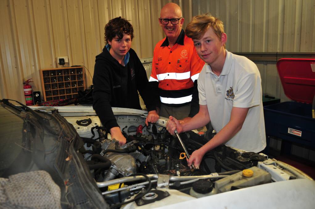 GREAT EXPERIENCE: Lachlan Elliott-Smith and Jamie Wright, Year 9, working on the engine of the donated car, with teacher Phill Schmarr.