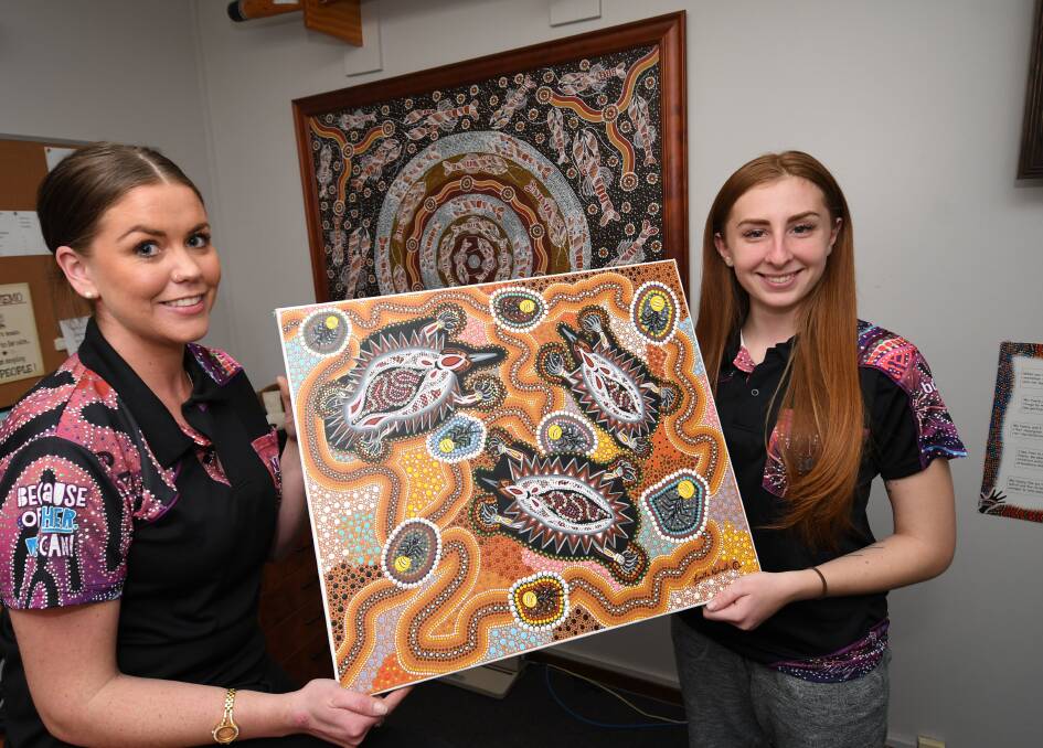 GOING NORTH: Courtney Glazebrook and Paige Debenham with an artwork to be raffled to assist disadvantaged Indigenous children in the NT. 