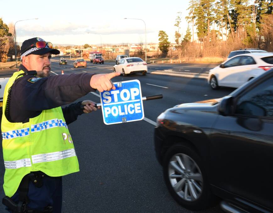 CURBING THE ROAD TOLL: Highway Patrol officer Senior Constable Aaron Unicomb directing motorists near Learmonth Park on Monday. Photo: CHRIS SEABROOK 061118crbt1