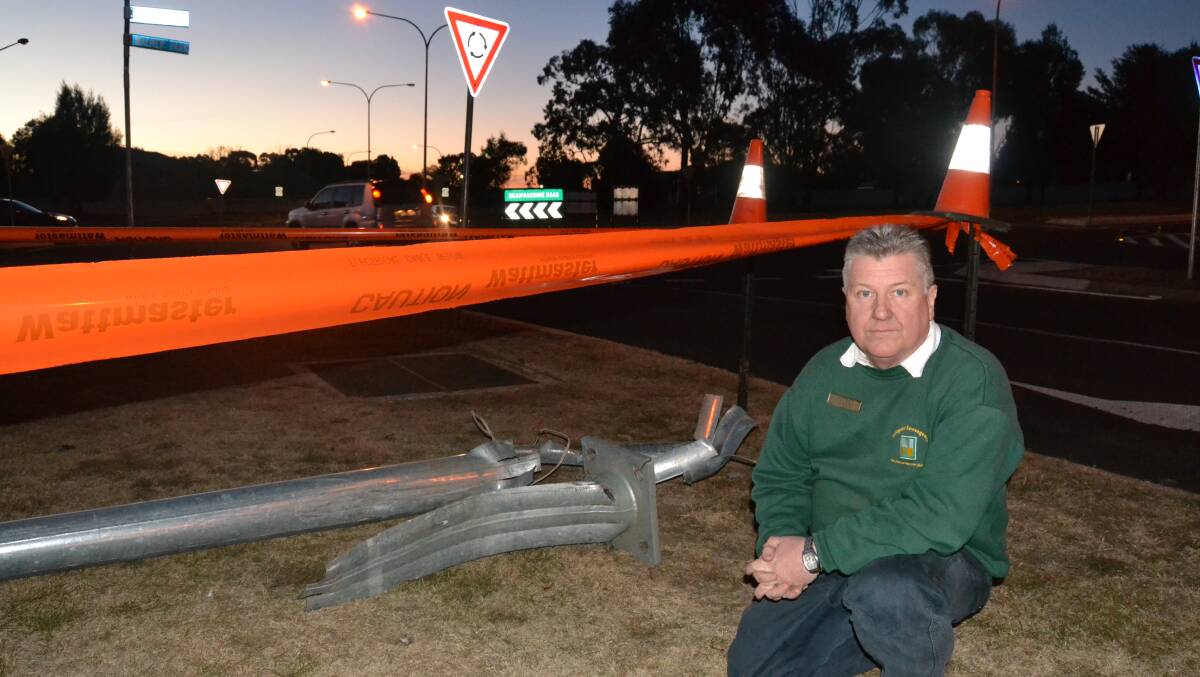 CRASH: Lachlan Sullivan, pictured in front of the Suttor Street roundabout, with the remains of a light pole which was flattened in a crash involving two vehicles on Tuesday.